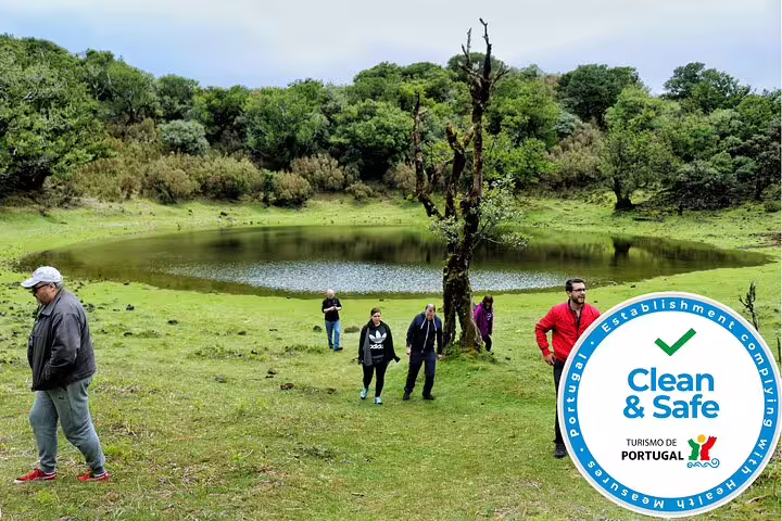 Tourists enjoy a guided walk near a tranquil volcanic pool, marked with a Clean & Safe Portugal certification.