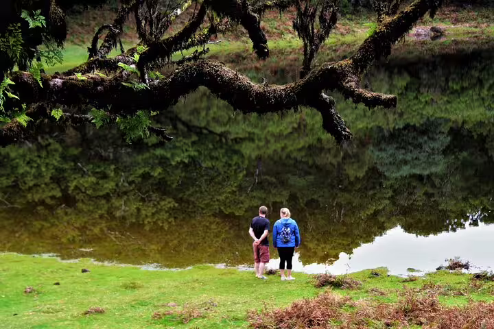 Two tourists admire the serene volcanic pool surrounded by lush greenery on a Northwest Terraces 4x4 shore excursion.