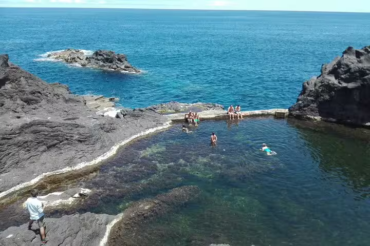 Visitors enjoying a refreshing swim in the natural volcanic pools amid stunning ocean views on the UNESCO tour.