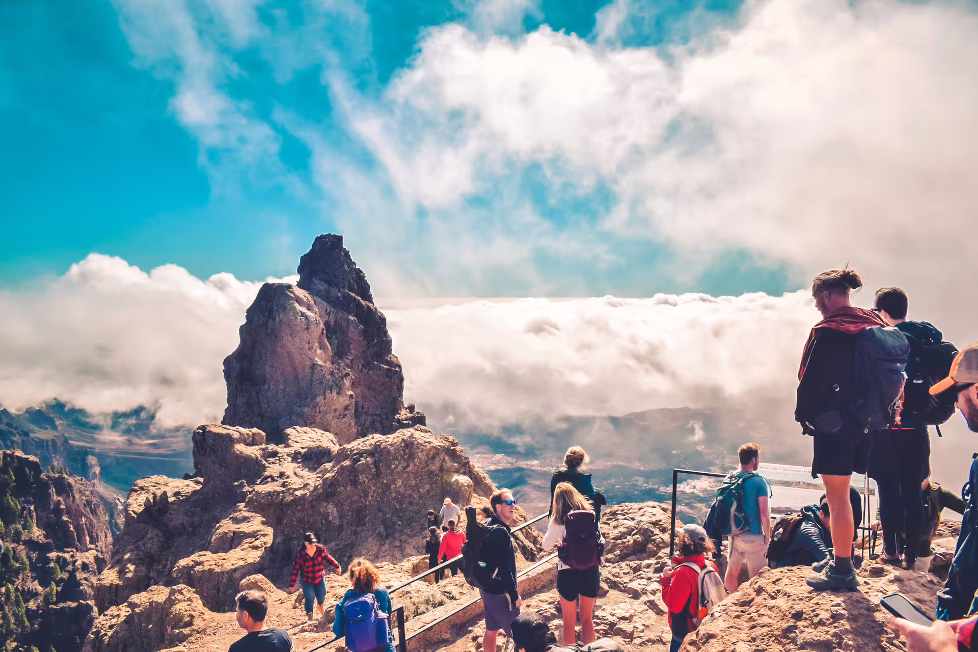 Hikers enjoy breathtaking views atop a volcanic peak, surrounded by clouds on the Volcano Heart Tour.