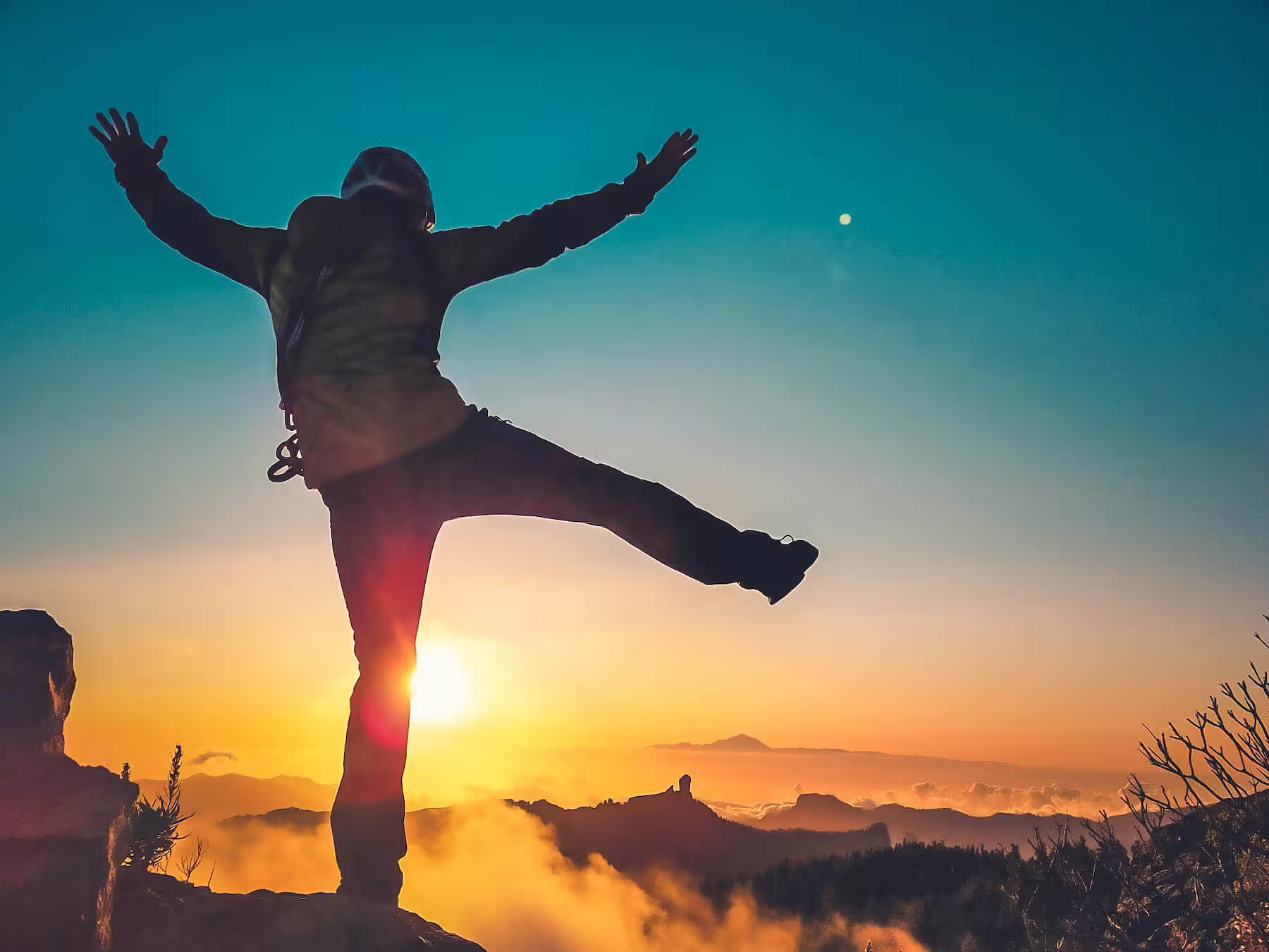 Adventurer celebrates sunrise atop a volcanic mountain, highlighting the thrill of the Volcano Heart Tour.