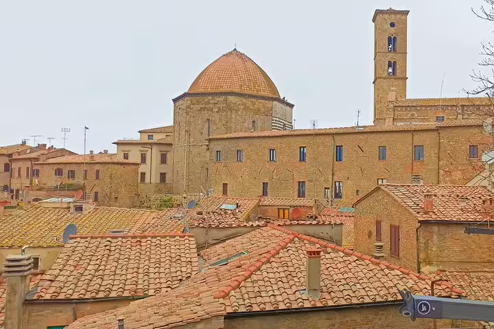 Rooftop view of Volterra’s medieval stone buildings and domed church, a highlight of private shore excursion from Livorno Port