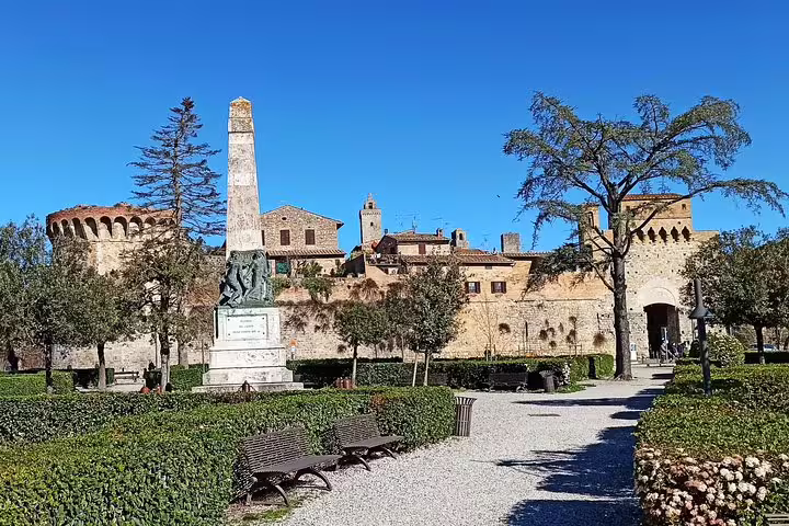 Historic gardens, statue and fortified walls of Volterra under a clear blue sky, featured on the private Tuscany wine tasting tour