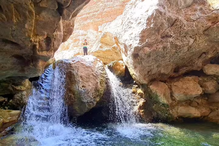 A stunning waterfall cascades over rocks at Wadi Al Arbeieen, perfect for adventure seekers on Oman tours.