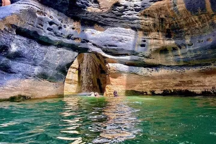 Swim beneath ancient stone arches in the tranquil waters of Wadi Dham during a private full-day exploration.