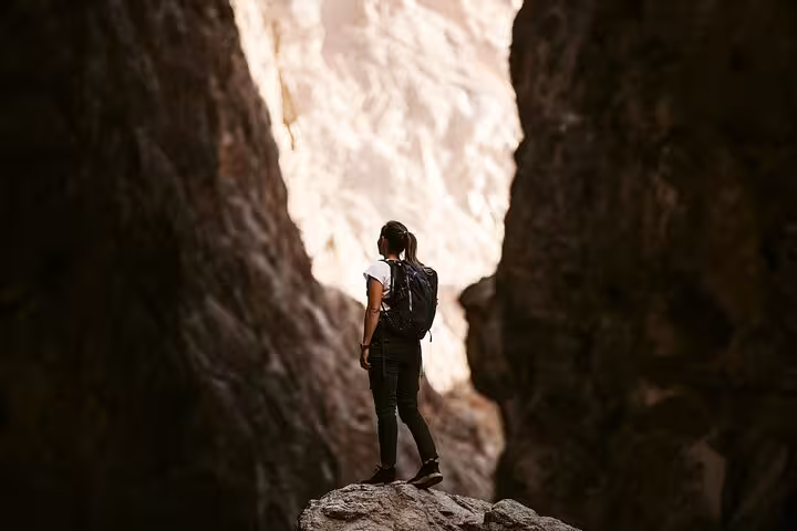 Solo hiker explores dramatic canyon walls on an adventurous Wadi Shab trekking day trip from Muscat, Oman