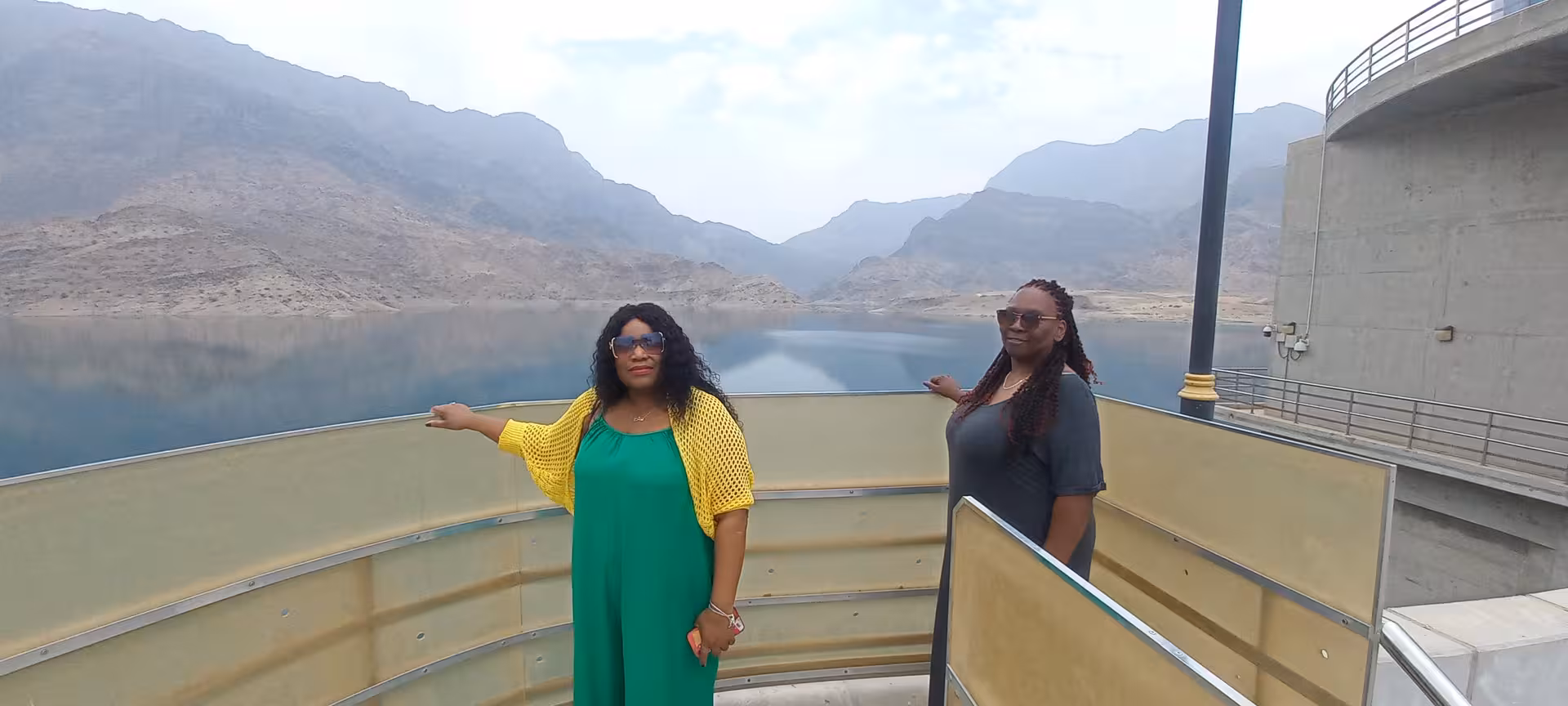Travelers admire the tranquil mountain reservoir and dramatic rocky cliffs on a Wadi Shab full day tour in Oman