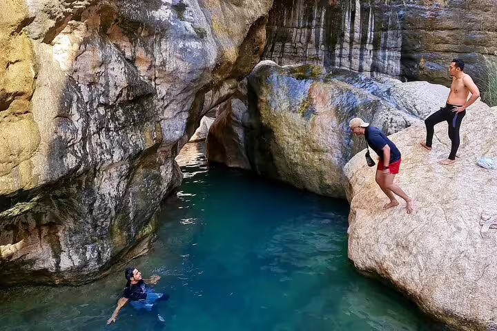 Adventurers preparing to dive into the clear waters of Wadi Tiwi, showcasing the thrill of a Muscat day trip.