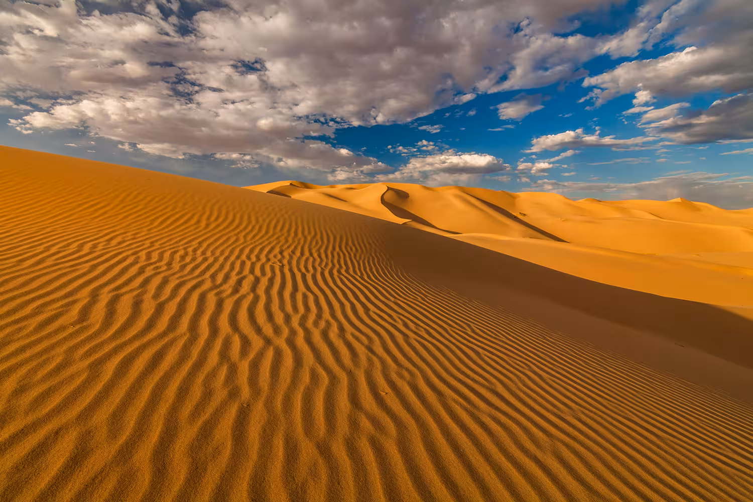 Golden dunes of Wahiba Sands desert under dramatic clouds, a scenic stop on the 3-day Nizwa, turtle watching and Wadi Shab tour
