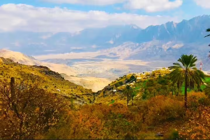 Expansive view of Wakan Village nestled in lush valleys with mountains as a backdrop on a Nakhal Hotspring tour.