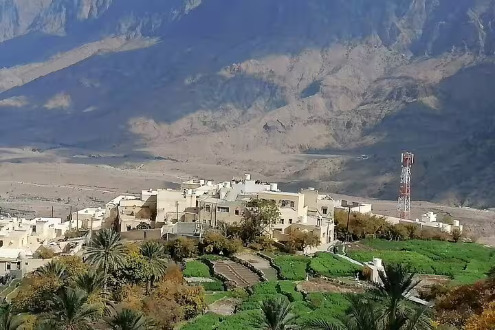 Panoramic view of traditional architecture and lush terraces in Wakan Village, nestled against majestic mountain backdrop.