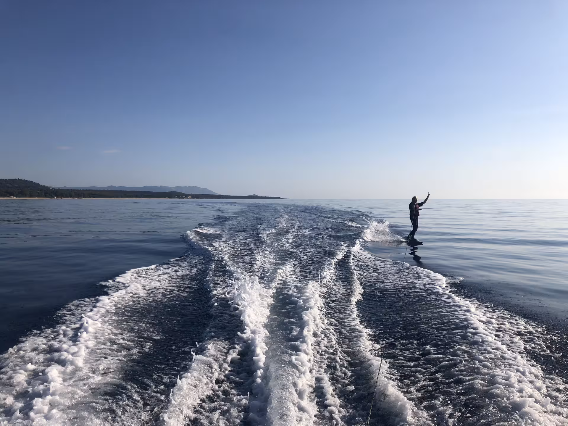 Person wakeboarding on tranquil sea in Bari Sardo, ideal for adrenaline seekers looking for a unique coastal adventure.