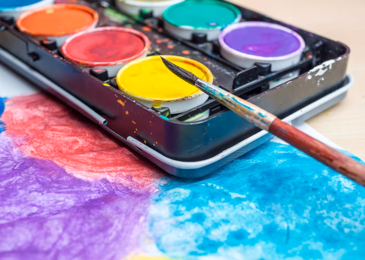 Vibrant watercolor palette and brush set for artistic classes at Prisons Palace painting workshop.