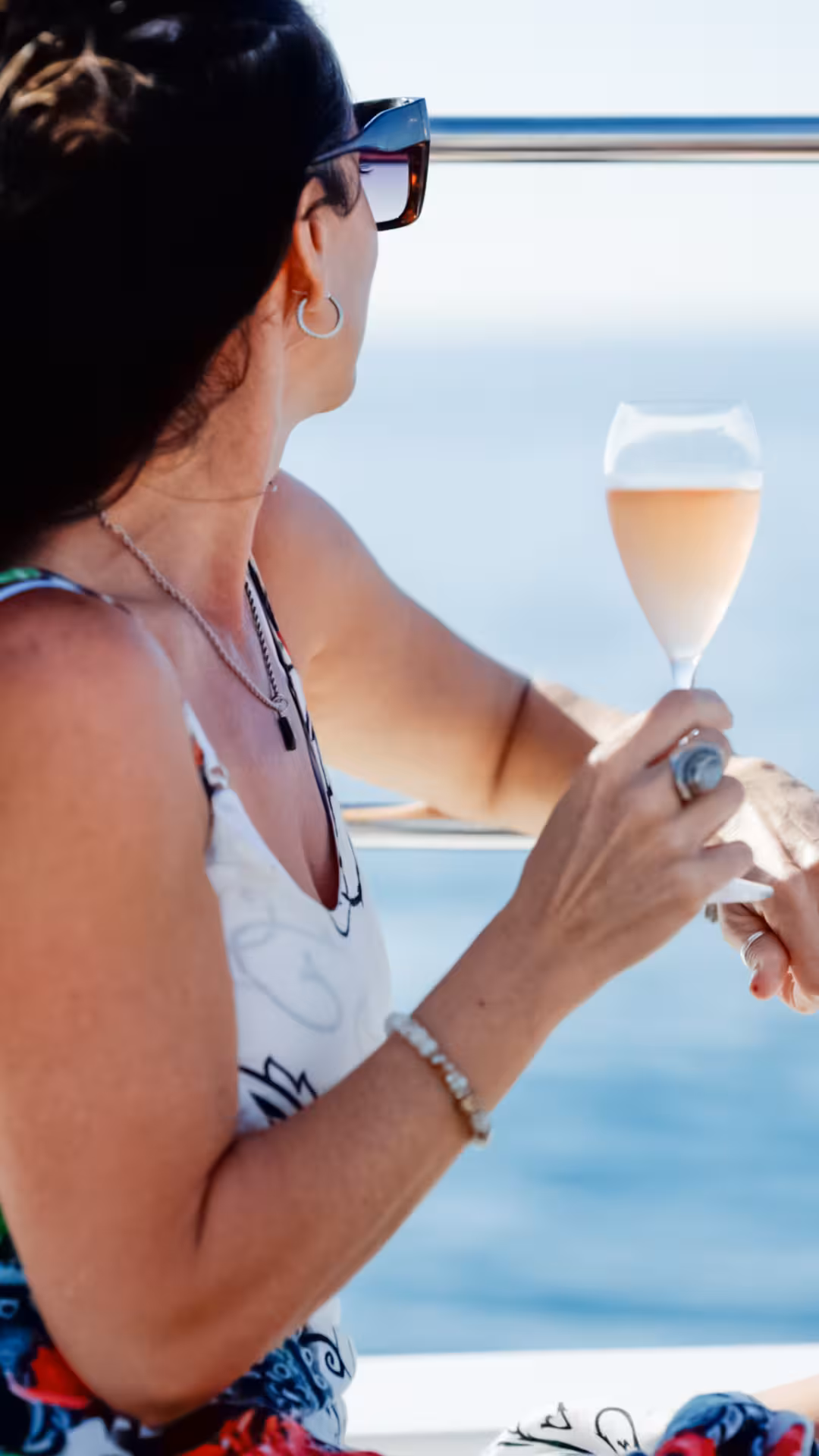 Guest on boat holding chilled rosé by the rail with ocean view, Wellness & Sea Breeze luxury sailing tour