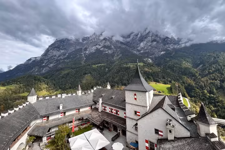 Werfen Castle courtyard and towers beneath dramatic Alps clouds on private Eagles Nest day trip from Munich