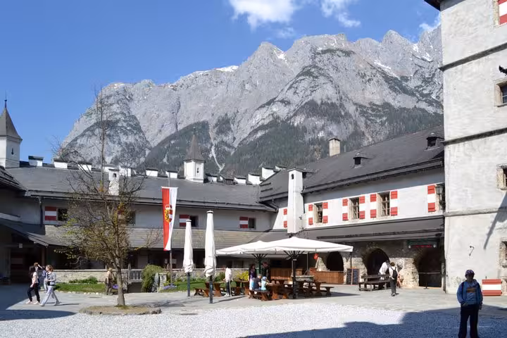 Visitors in Werfen Castle courtyard beneath towering Alps on Eagles Nest and Werfen Castle private tour from Munich