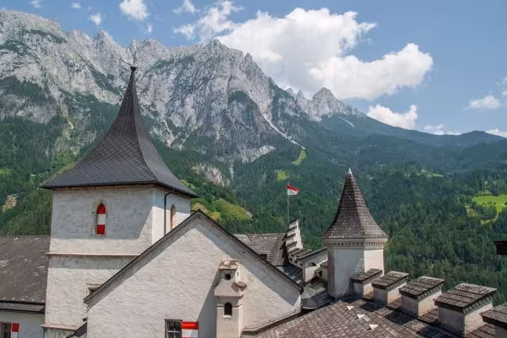 Werfen Castle towers with Austrian flag and Berchtesgaden Alps backdrop on Eagles Nest private tour from Salzburg