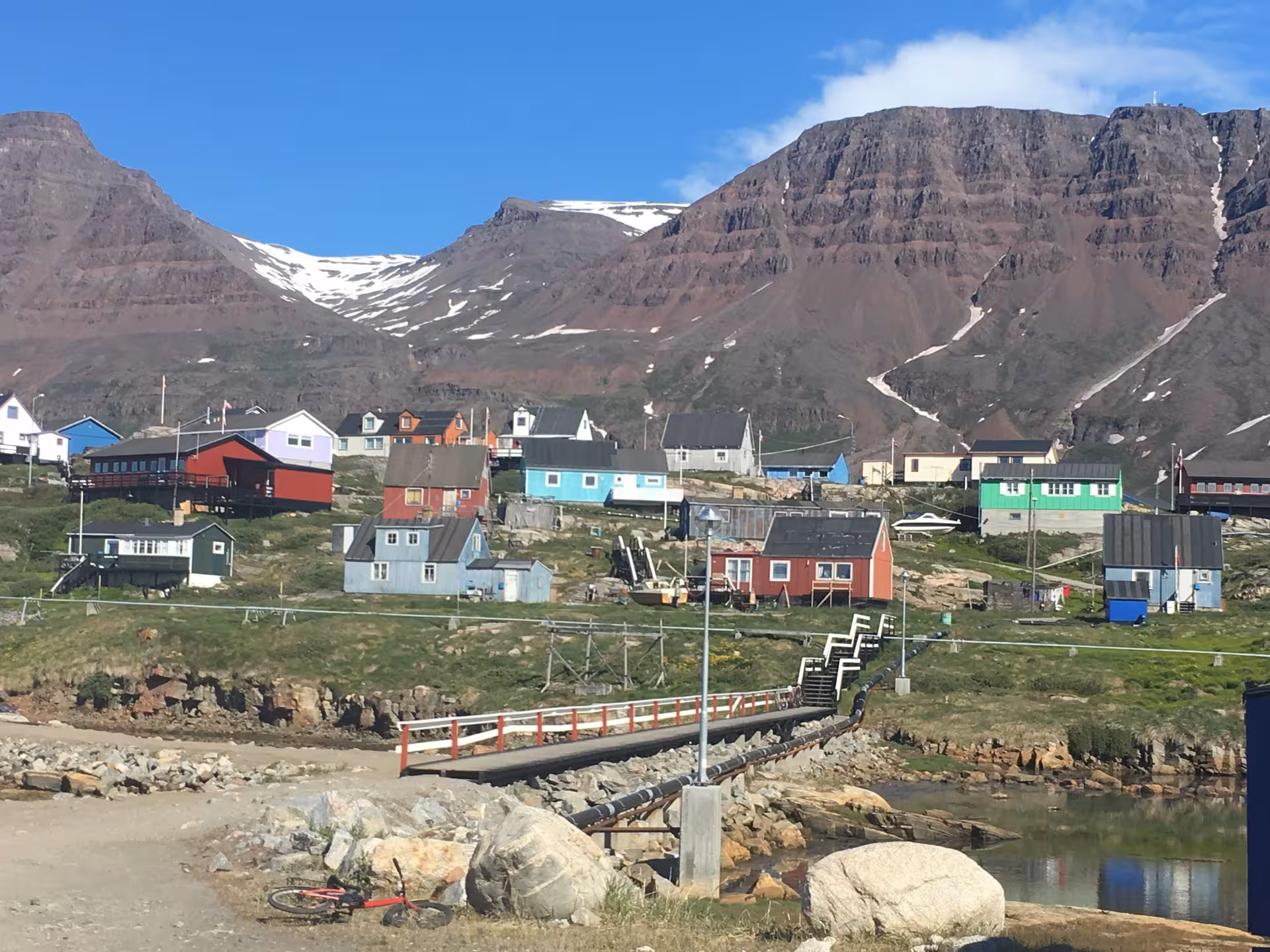 Colorful houses nestled in the scenic mountains of West Greenland, showcasing traditional Greenlandic village life.