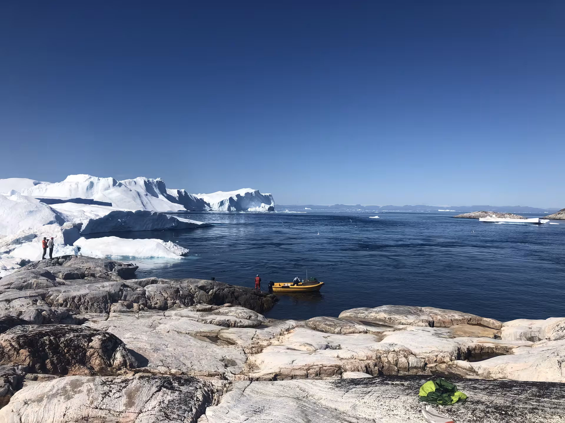 Scenic view of icebergs and a small boat on the waters of West Greenland, perfect for adventurous exploration.