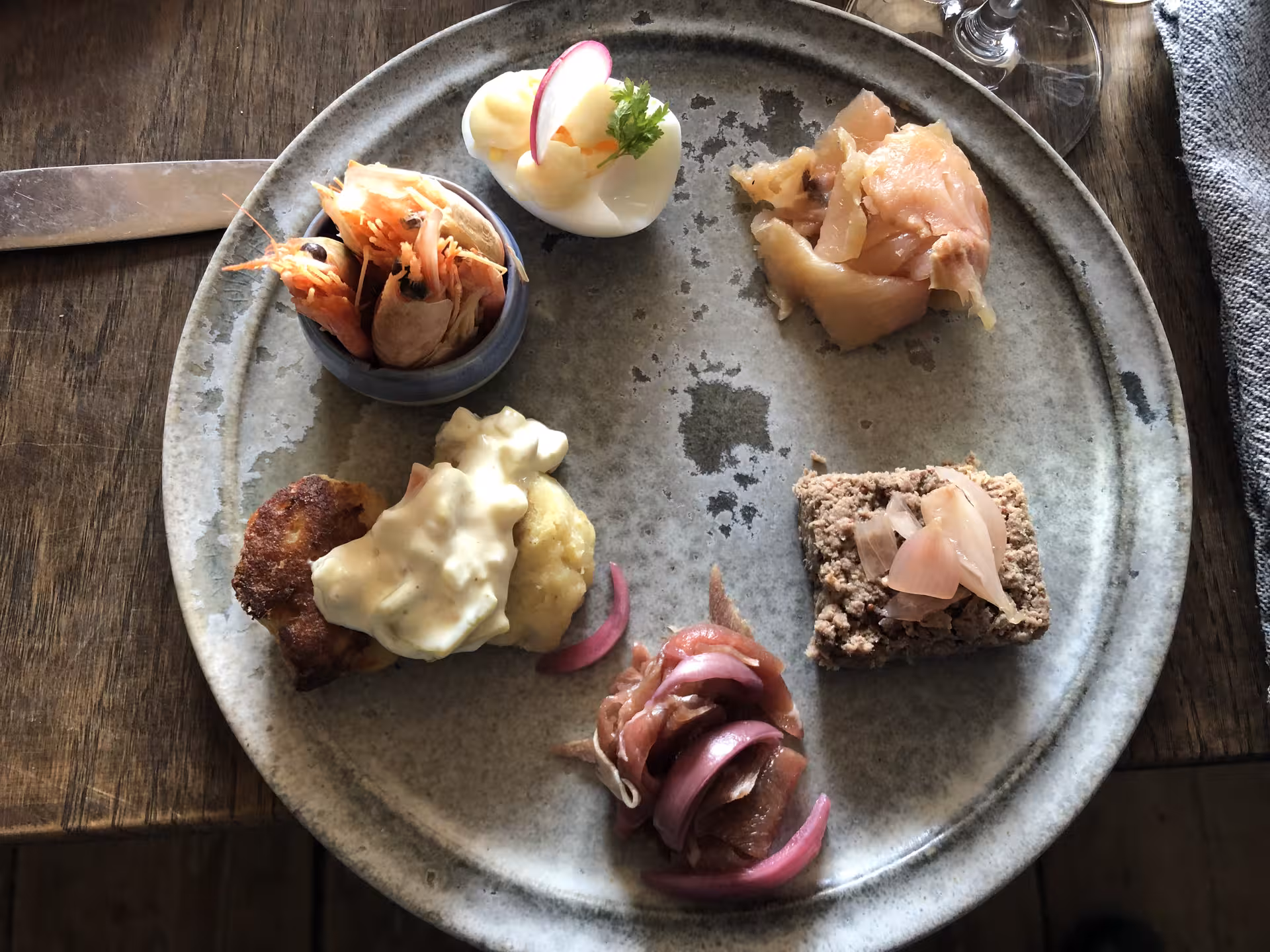 A diverse Greenlandic seafood platter featuring shrimp, fish, and pâté, showcasing West Greenland's culinary delights.