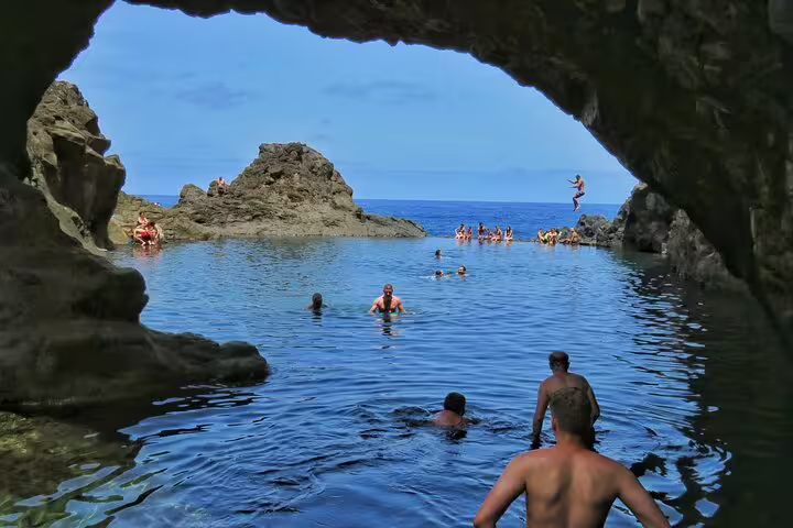 Tourists enjoy swimming and cliff diving in a natural rock pool on a full-day private 4x4 tour in West Madeira.