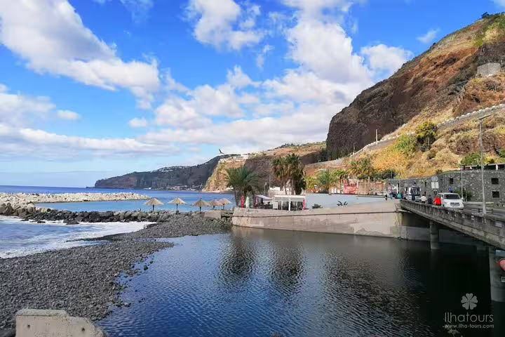 Scenic coastal view at West Tour destination featuring a tranquil bay, rocky shoreline, and vibrant blue sky.