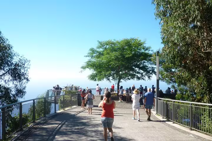 Visitors stroll towards a scenic viewpoint on the West Tour, surrounded by lush greenery and ocean vistas.