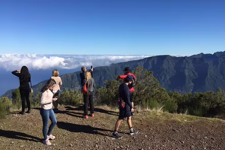 Tourists capturing breathtaking views of lush mountains and clouds on the UNESCO 4x4 tour.
