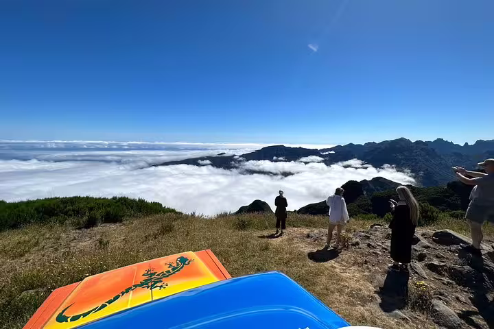 Tourists enjoy a breathtaking view above the clouds from a mountain peak, captured during the Unesco 4x4 Tour.
