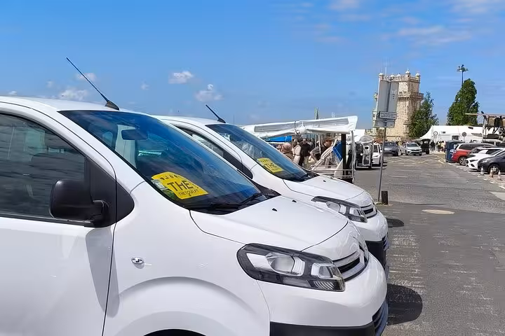 White airport shuttle vans lined up for Lisbon Airport to city center transfer, ready for pickup service