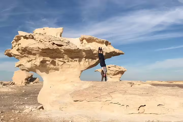 Traveler posing by mushroom-shaped chalk rock in Egypt’s White Desert on a private day tour to Bahariya Oasis