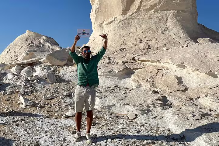 Visitor celebrating beside chalk rock formations on Private Day Tour to Egypt’s White Desert and Bahariya Oasis