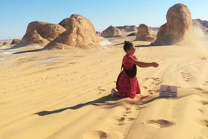 Traveler tossing sand among dunes and rock formations on a private White Desert and Bahariya Oasis day tour