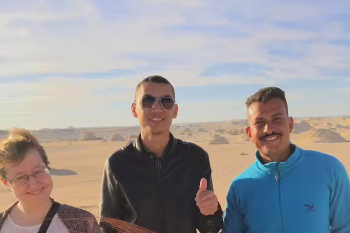 Guests and local guide smile in Bahariya Oasis desert during a private White Desert day trip from Cairo