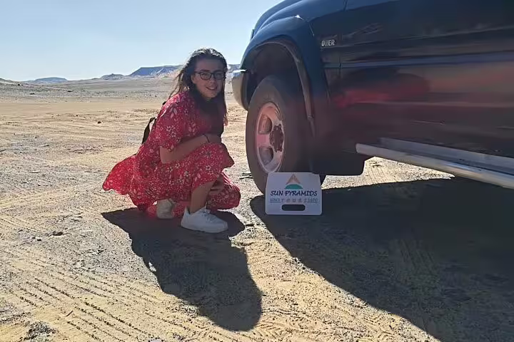 4x4 desert safari stop on private White Desert and Bahariya Oasis day tour, traveler posing by off-road vehicle