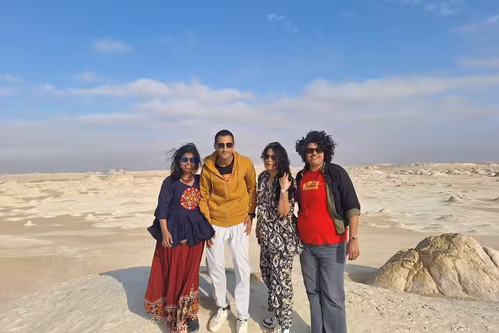 Group of friends enjoy the stunning landscapes of the White Desert, showcasing the unique rock formations on a sunny day.
