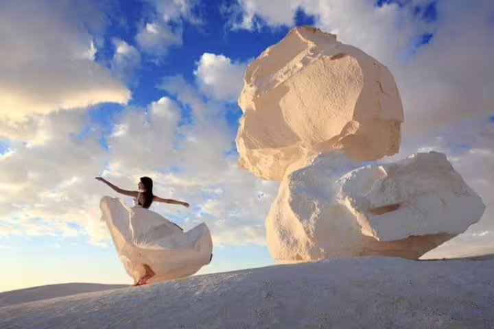 Traveler posing by giant chalk formations at sunset in White Desert, Egypt, on private 2-day jeep safari tour