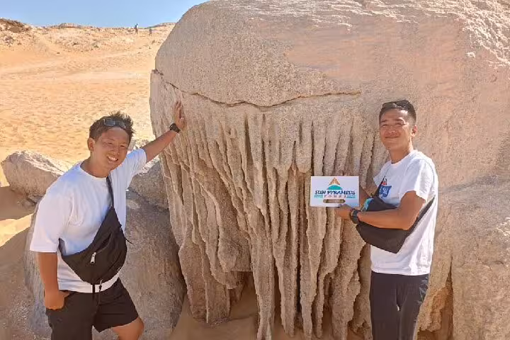 Travelers beside unique White Desert rock formation on a private 4-day Bahariya Oasis and White Desert tour