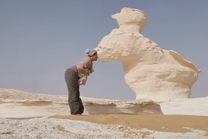 Tourist posing by iconic White Desert rock formation, highlight of private 2-day Black and White Desert safari