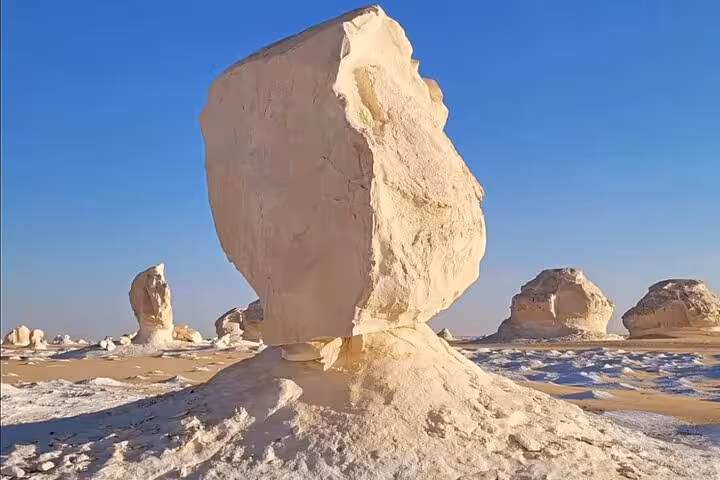 Close-up of striking white rock formations in the White Desert under a clear blue sky, ideal for an overnight camping adventure.