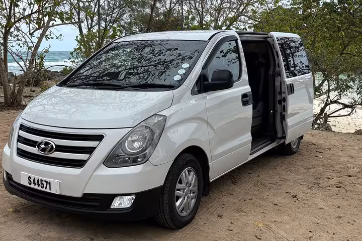 White Hyundai minivan with open door, offering private beachside transfers in Seychelles.