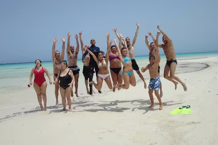 Tour guests jumping on White Island sandbar during Ras Mohamed VIP boat snorkeling excursion from Sharm