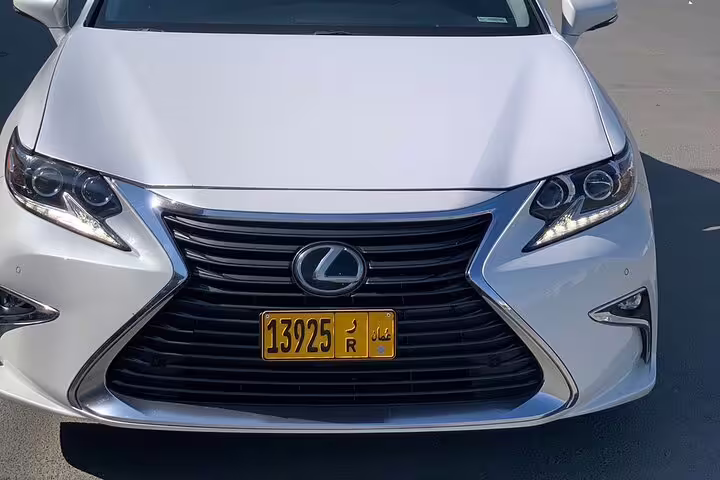 Front view of a modern white luxury car, showcasing its elegant design and Omani license plate for Muscat tours.