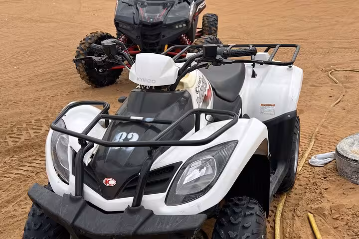 White quad bike parked on desert sand, ready for guided dune bashing ATV ride and off-road adventure tour