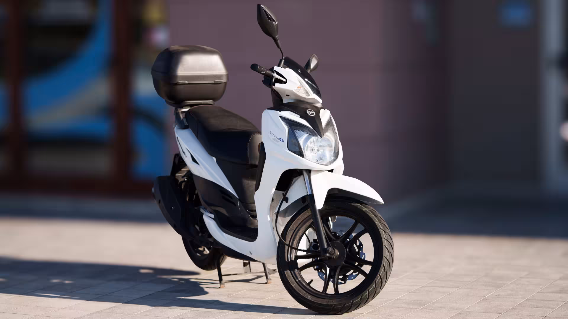 Stylish white scooter with a black seat and storage case available for rent in Olbia, ideal for city exploration.