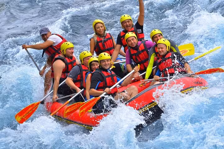 Group white water rafting in helmets on roaring rapids, part of great threesome rafting buggy zipline tour