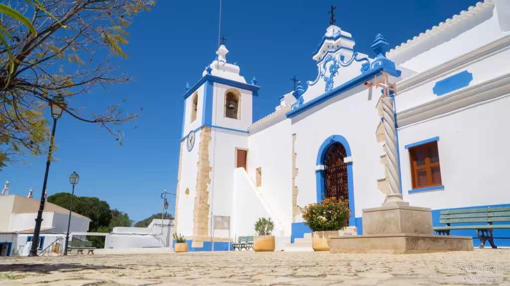Whitewashed church with blue trim and bell tower under clear Algarve sky on Landscapes and Traditions Arade River tour