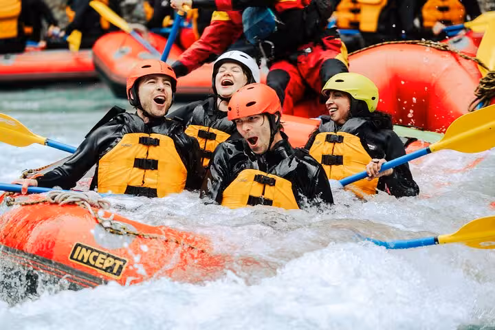 Group of rafters enjoying thrilling whitewater action in Engadin, paddling through rapids with vibrant helmets and life vests.