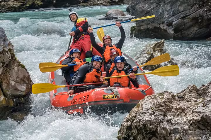 Adventurous group tackling rapids on a whitewater rafting trip in Engadin, surrounded by rocky landscape.