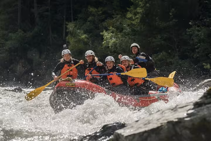 Adventurous group enjoying a dynamic whitewater rafting experience in Engadin, paddling through intense rapids with enthusiasm.